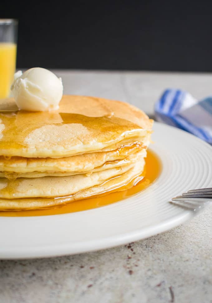 stack of homemade pancakes with maple syrup and butter on a plate