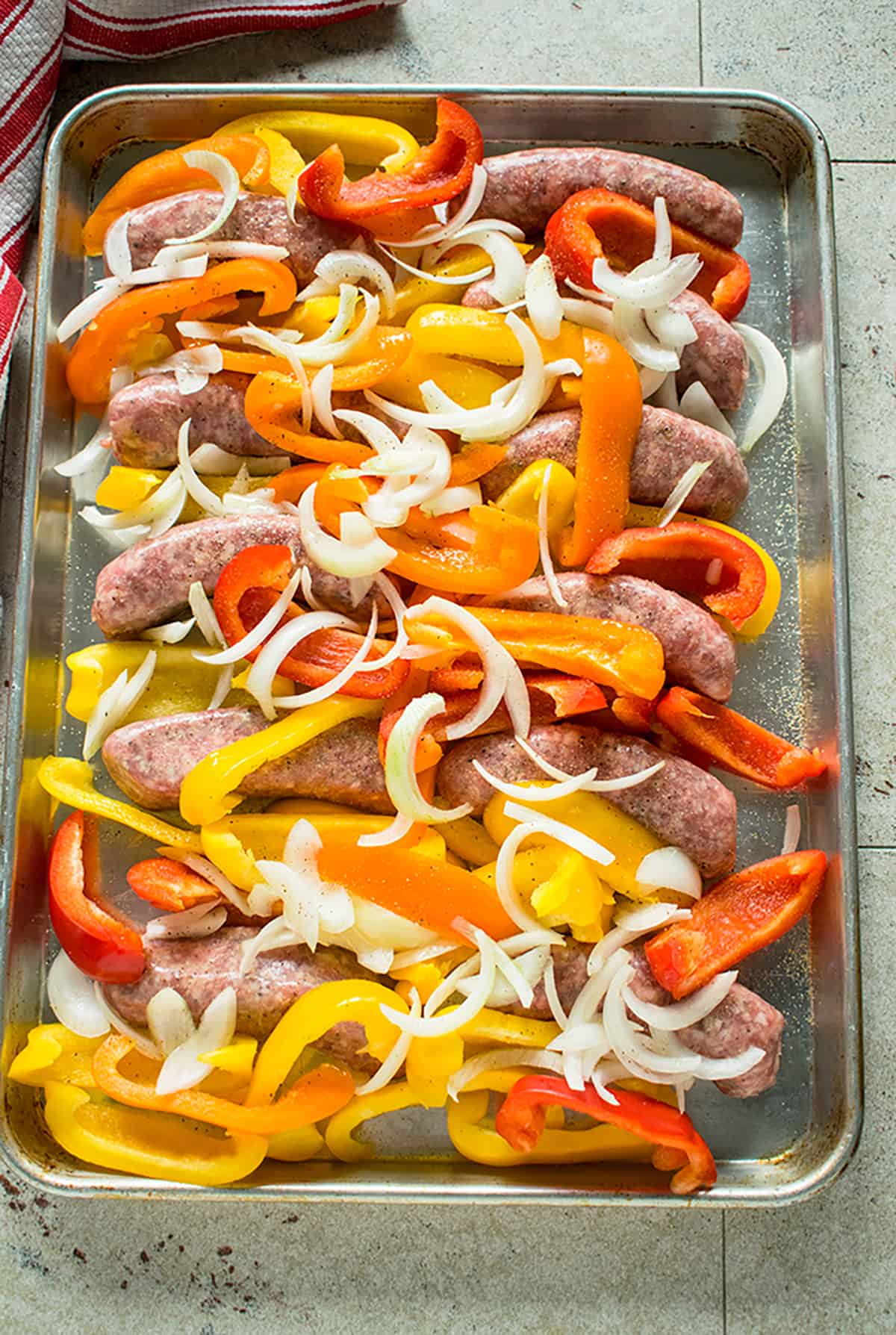 raw sausage links, sliced onions, peppers on sheet pan