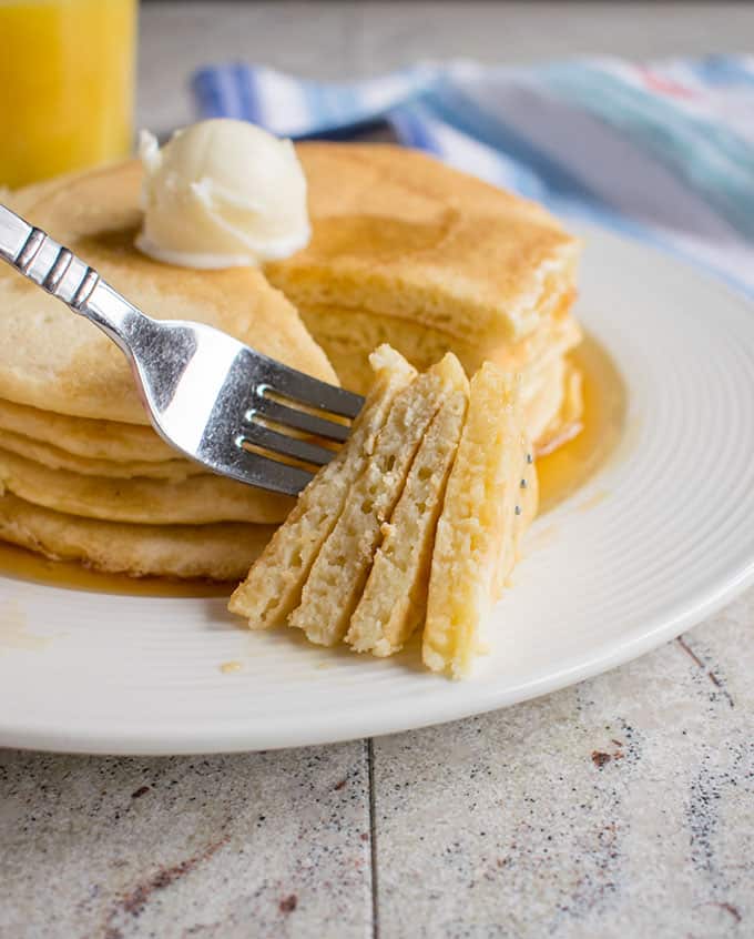 forkful of pancakes being taken from a stack of pancakes on a plate