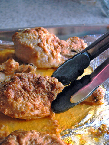 Tongs going to pick up a Parmesan Chicken Drumstick with Garlic Butter