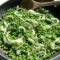 peas and onions in a pan with wooden spoon