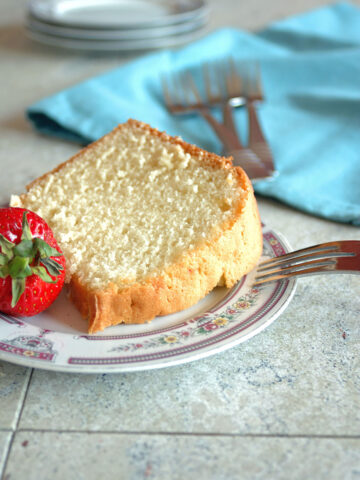 slice of pound cake on a plate with strawberry and fork