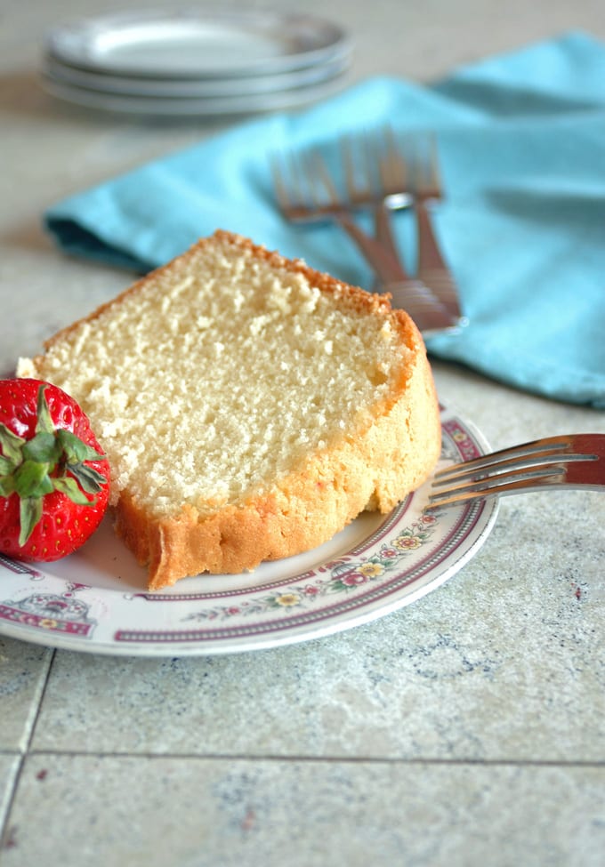 close-up of a slice of pound cake on a plate with strawberry and fork