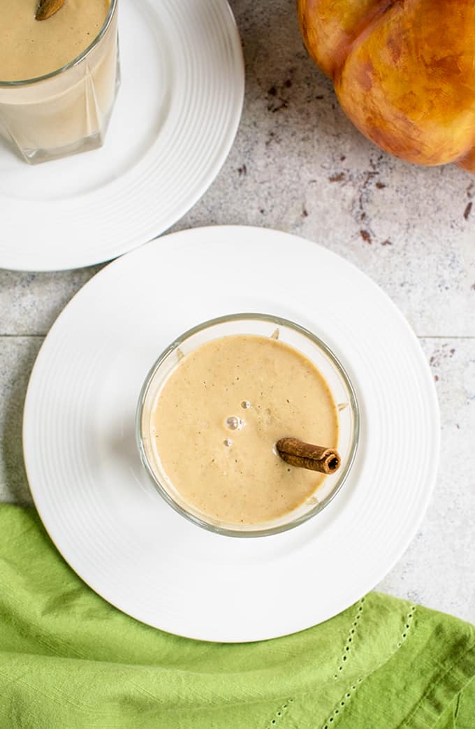 Overhead photo of pumpkin smoothie with cinnamon stick in a glass