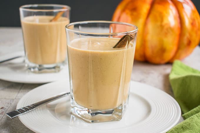 two pumpkin smoothies in glasses with cinnamon sticks inside