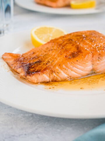ten minute maple-glazed salmon on a plate with a slice of lemon