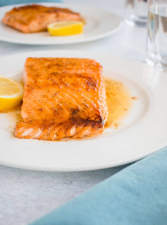 side view of 10-minute maple-glazed salmon on a plate with a slice of lemon