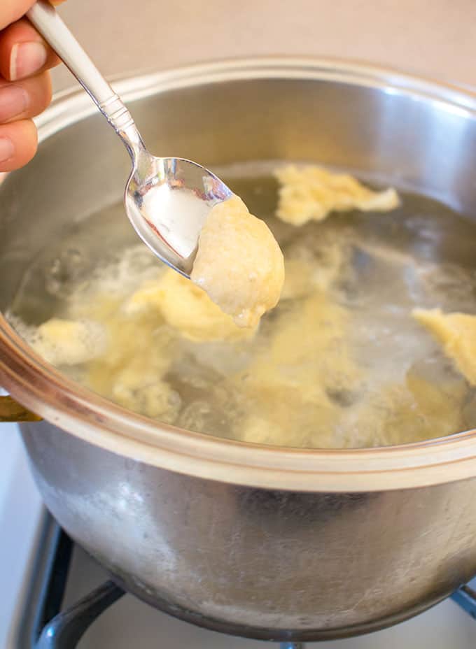 photo of spoonful of dumpling batter over a pot of water with dumplings cooking for hungarian chicken paprikash with dumplings 