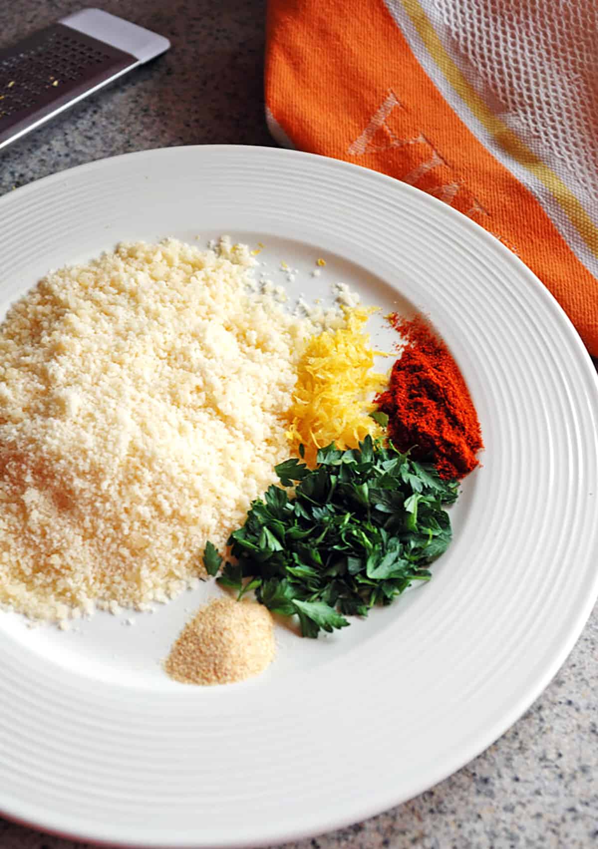 Photo of a plate with Parmesan, parsley and seasonings for Lemon Parmesan Cod with Garlic Butter