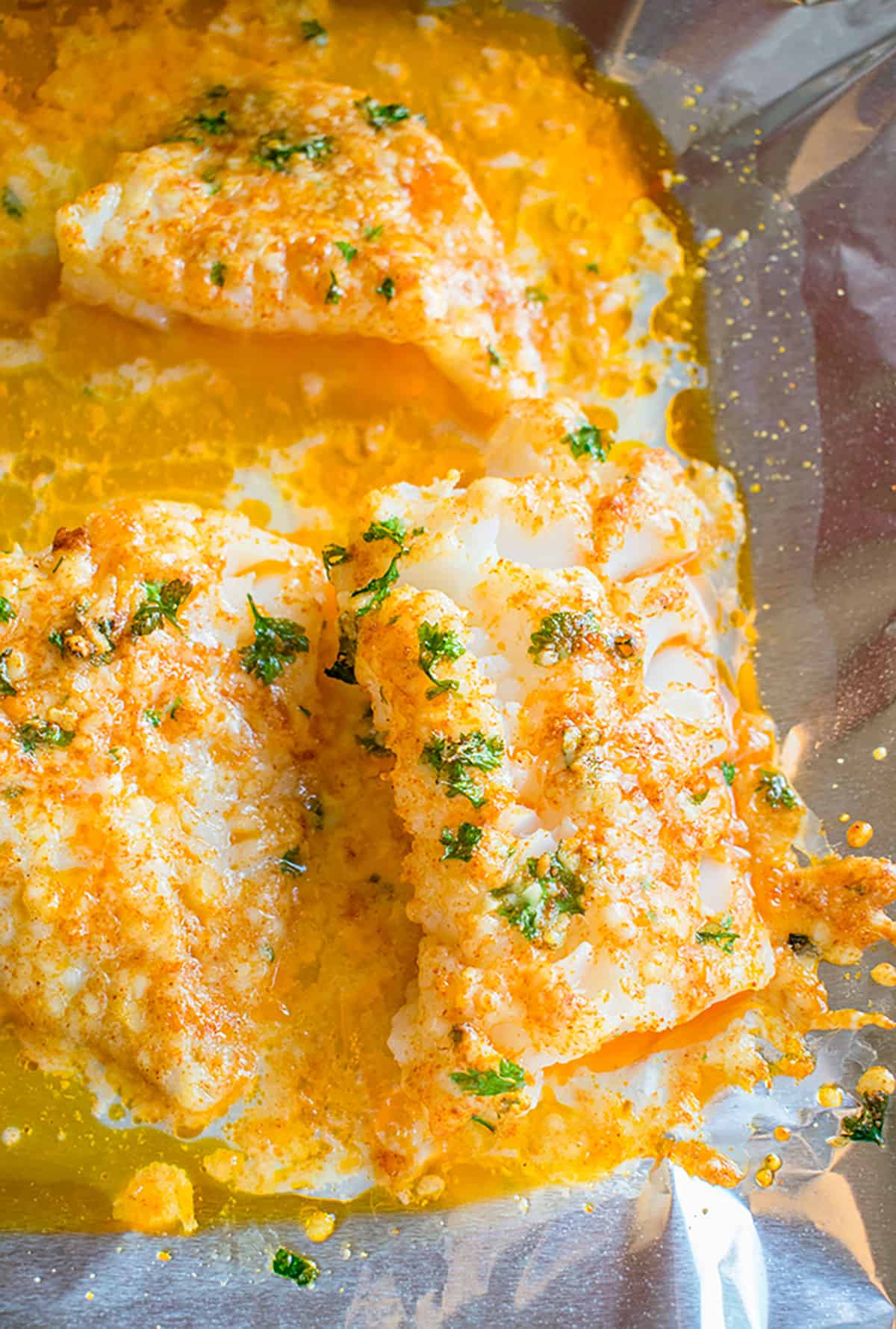 Close-up, overhead view of baked Cod with Parmesan in melted butter