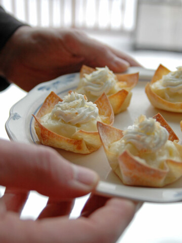 hands holding a plate of coconut cream pie cups