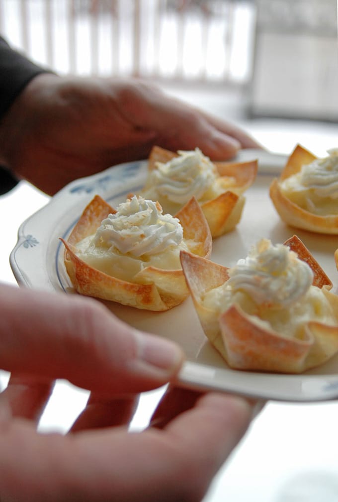 hands holding plate of coconut cream pie cups