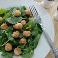 breaded scallops over salad with lemon vinaigrette on a plate with fork