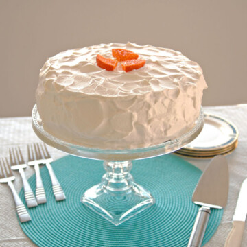 Orange Torte with Whipped Cream on stand, pie server, forks