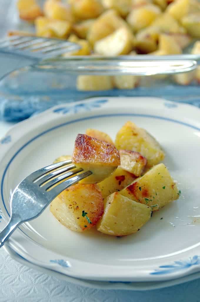 fork taking a piece of oven roasted potato with seasonello from the plate