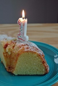 Slice of cake with a burning 1 candle on it