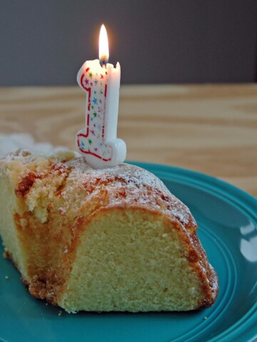 Slice of cake with a burning 1 candle on it