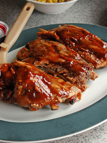 Slow Cooker BBQ Ribs on a plate with dressing brush