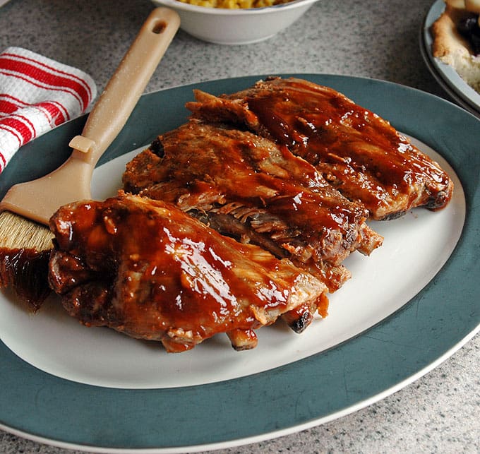 Slow Cooker BBQ Ribs on a plate with dressing brush
