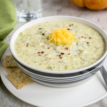 bowl of broccoli-cheddar soup on a plate with crackers