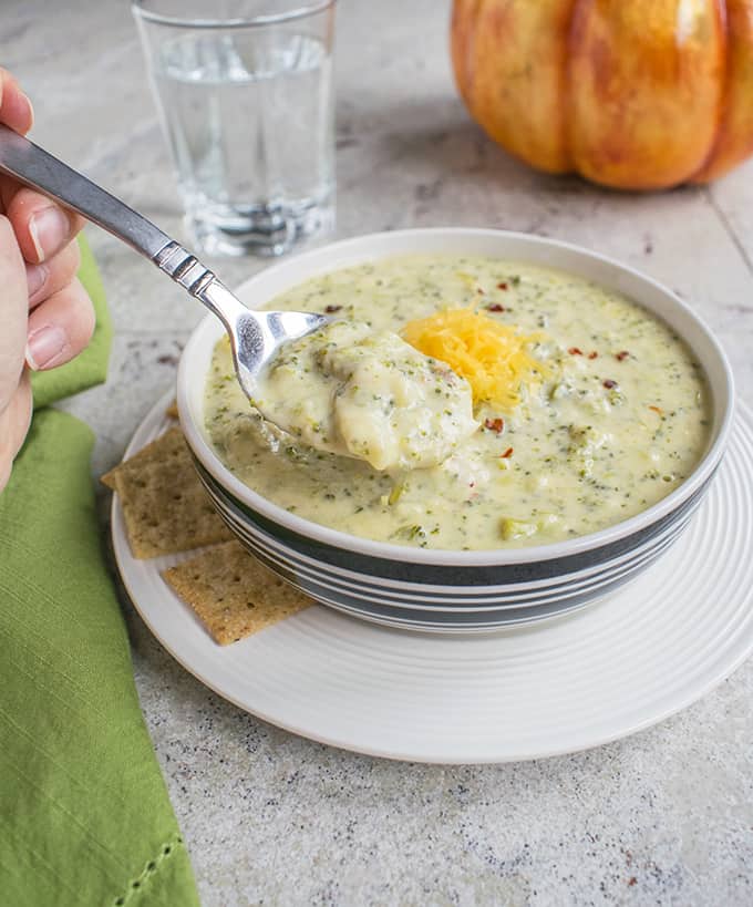 Photo of a spoonful of Broccoli-Cheddar Soup with Parmesan from a bowl with crackers