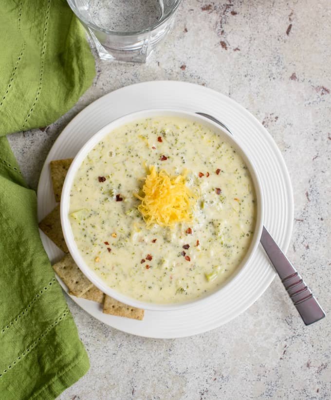 overhead photo of broccoli-cheddar soup with parmesan in a bowl with crackers