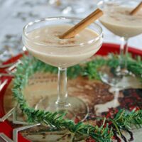 Coquito (Coconut-Rum Drink) in a martini glass with cinnamon stick
