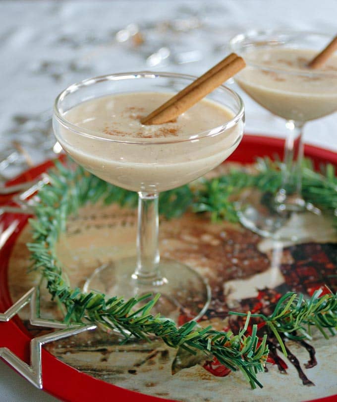 Coquito (Coconut-Rum Drink) in a martini glass with cinnamon stick