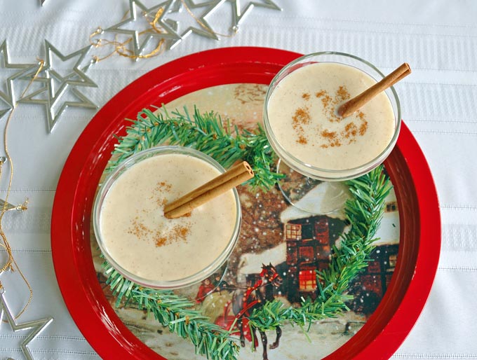 overhead view of two martini glasses of Coquito (Coconut-Rum Drink) with cinnamon sticks