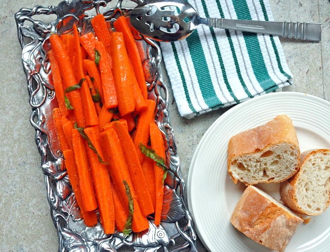 platter of Italian Carrot Salad with Basil next to bread and a napkin with serving spoon