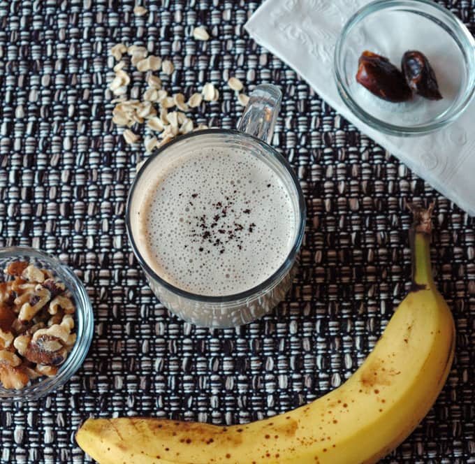 overhead view of Espresso Banana Smoothie with 2 dates, oats, a banana and walnuts