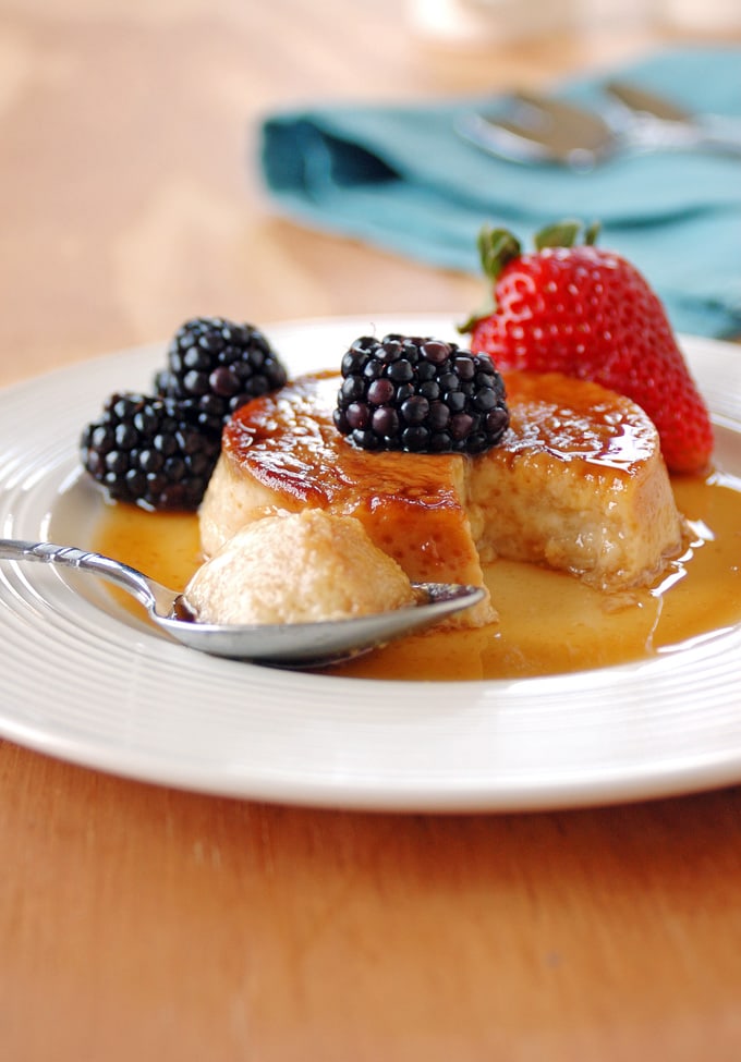 spoonful of Low Fat Maple Flan with Berries resting on a plate in front of the flan