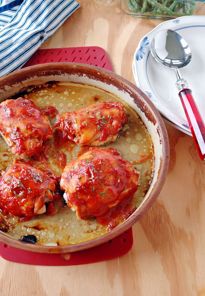 4-ingredient BBQ Chicken in a cooking dish next to a plate with a spoon on it