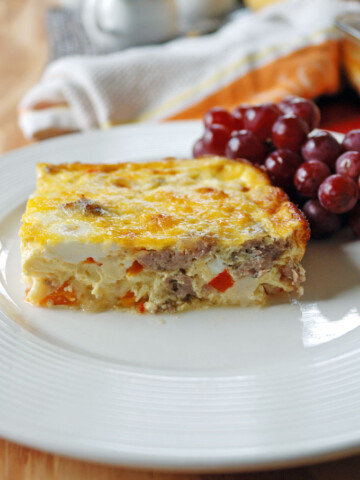 close-up photo of a plate with a piece of Sausage and Peppers Breakfast Casserole and grapes