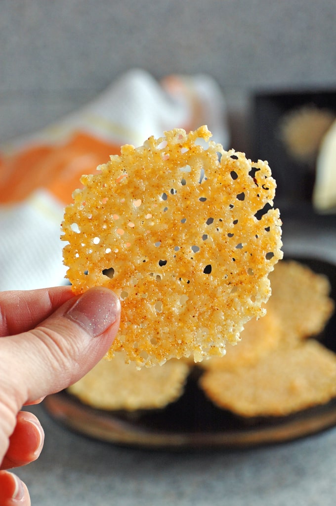 Parmesan crisp being held between thumb and finger