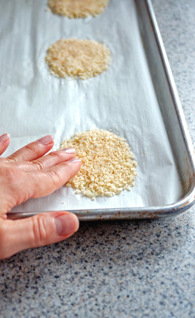 patting down mound of grated Parmesan in sheet pan