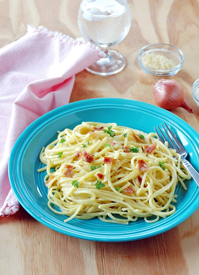 Pasta Carbonara with Shallots in a blue bowl with a fork