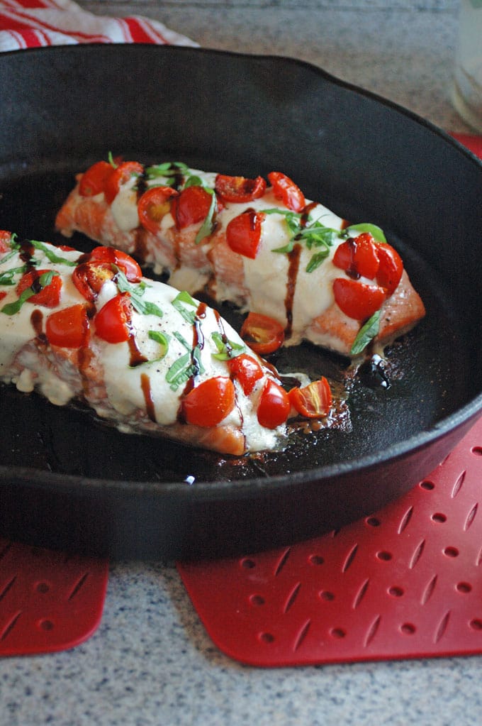 vertical photo of Salmon Caprese with Balsamic Glaze in an iron skillet