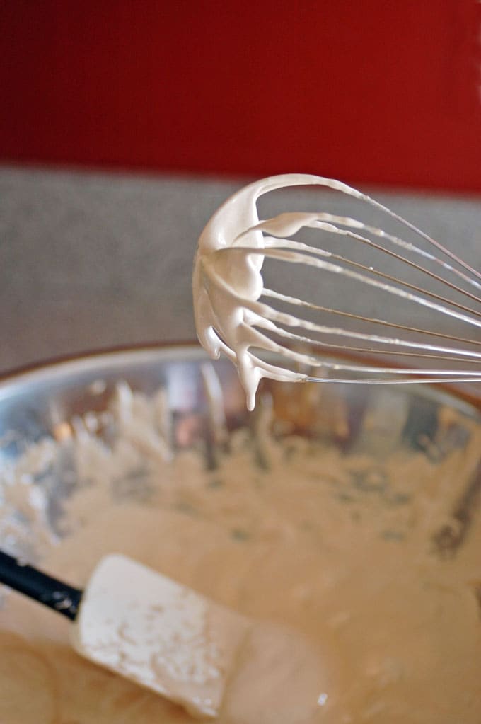 whisk with meringue dripping, bowl of meringue with spatula 