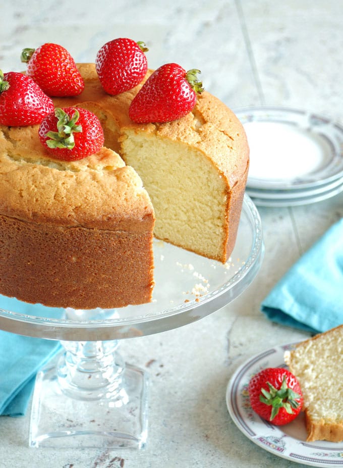Low-fat pound cake with strawberries with piece cut out on cake platter 