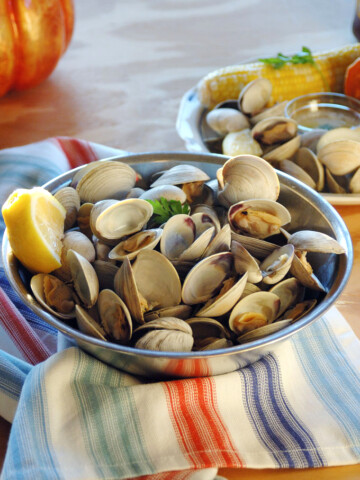 Bowl of uncooked littleneck clams with lemon