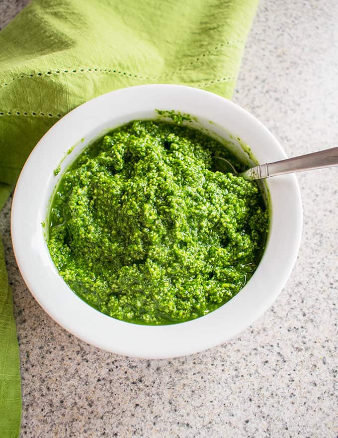 Photo of white bowl filled with Pesto with Pecorino Romano and a spoon dipped in it