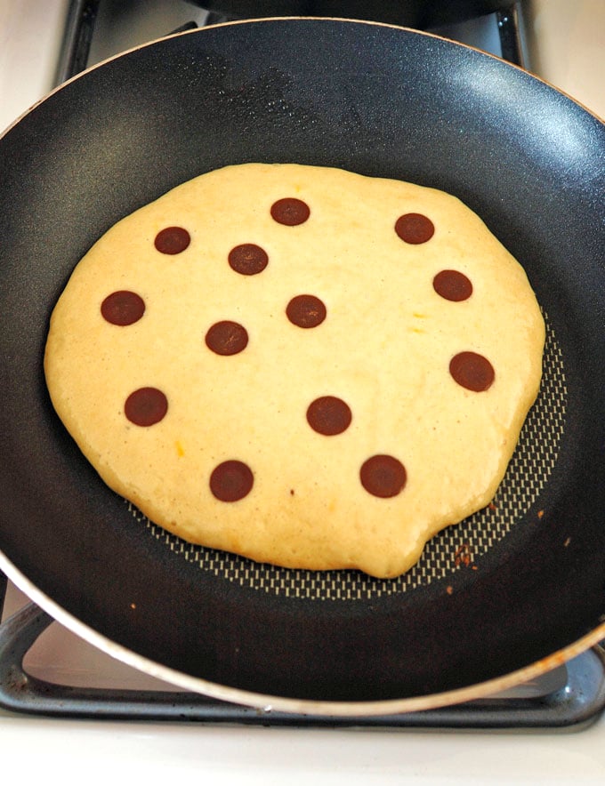 chocolate chip pancake cooking in pan on stove