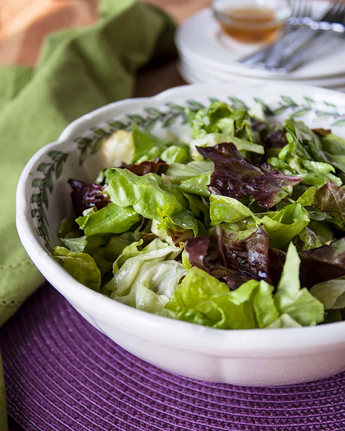 bowl of green salad with dressing in background