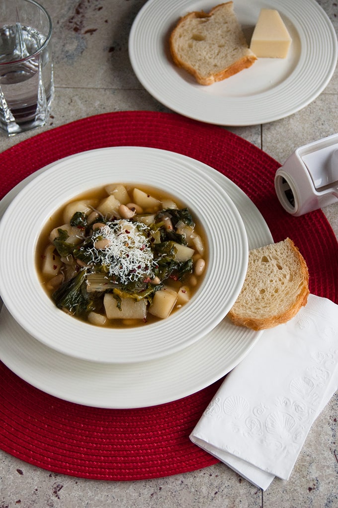overhead view of soup with escarole, beans and potatoes, bread and cheese 