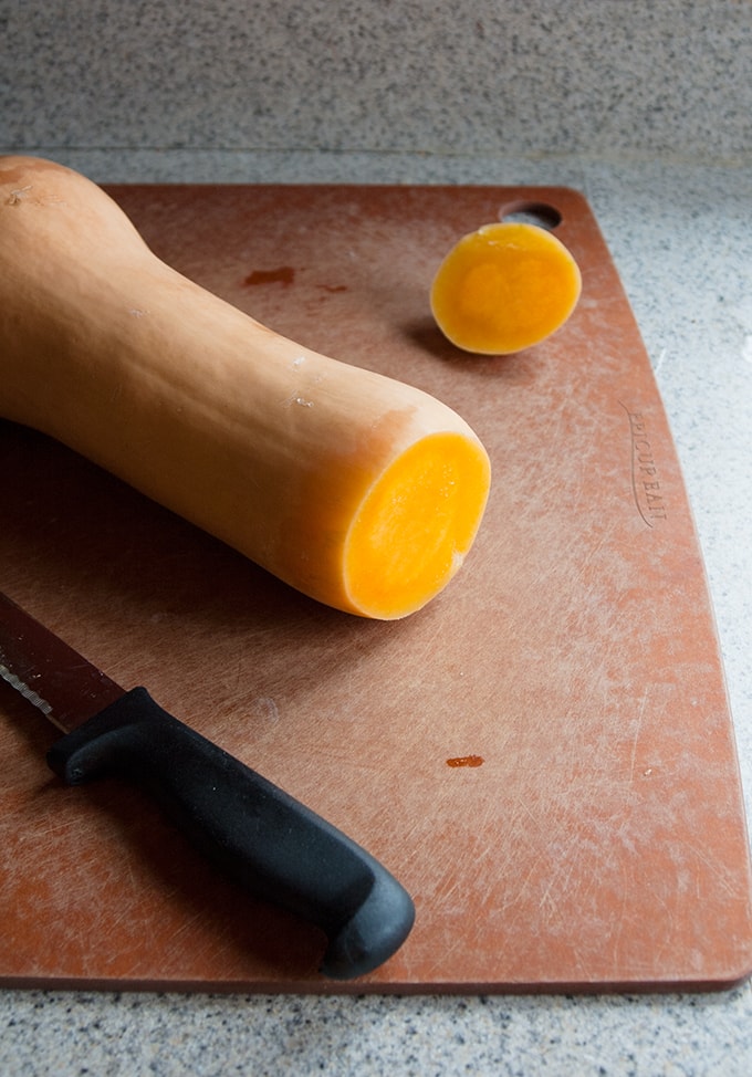 butternut squash on a cutting board with a knife 