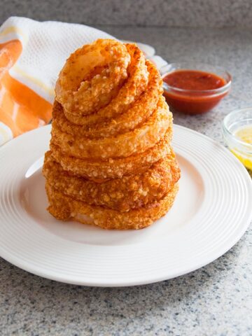 stack of baked parmesan gluten-free onion rings on a plate