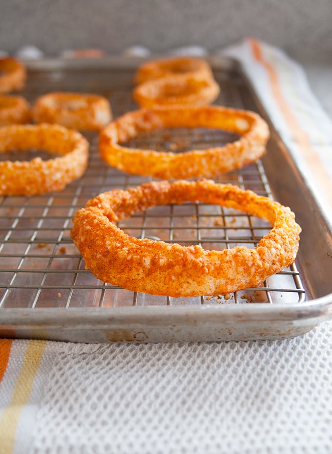 baked parmesan gluten-free onion rings on a cooling rack in a sheet pan 