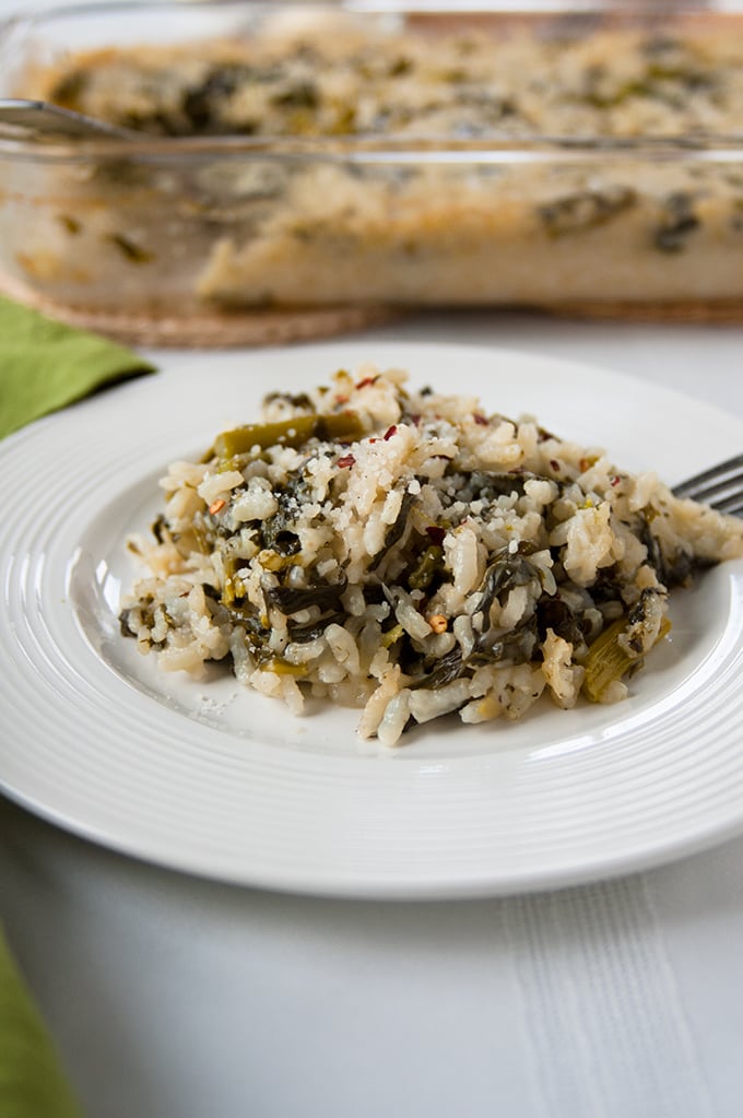 Baked Vegetable Risotto with Asparagus and Spinach on a plate with a fork, in front of glass pan