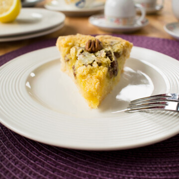 slice of lemon pie with pecans on a plate with a fork
